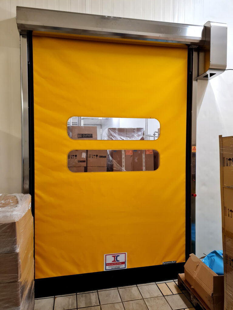 Porta rapida industriale gialla con oblò trasparenti installata nell’area produttiva Lattebusche.