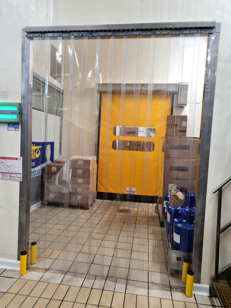 Tenda in PVC trasparente installata davanti a porta rapida per ridurre la dispersione termica nelle aree frigorifere Lattebusche.